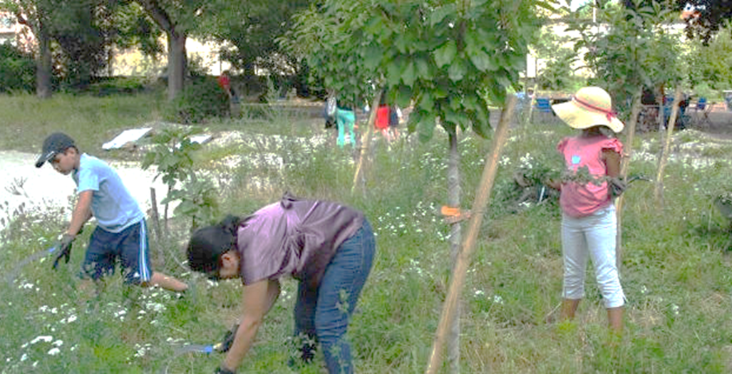 Une femme et deux enfants font du jardinage dans le quartier Mermoz