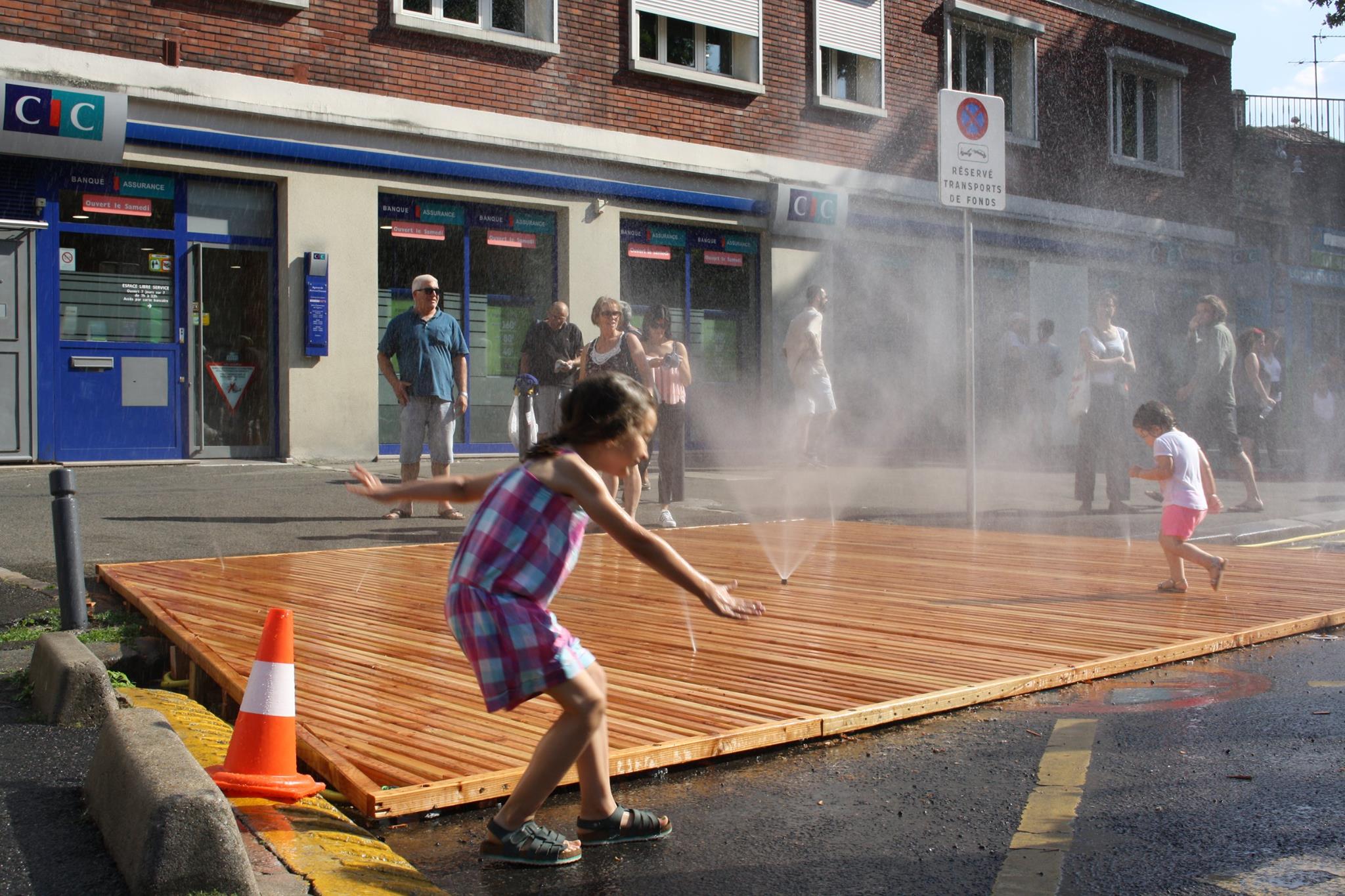 Enfants jouant avec des jets d'eau sur la place