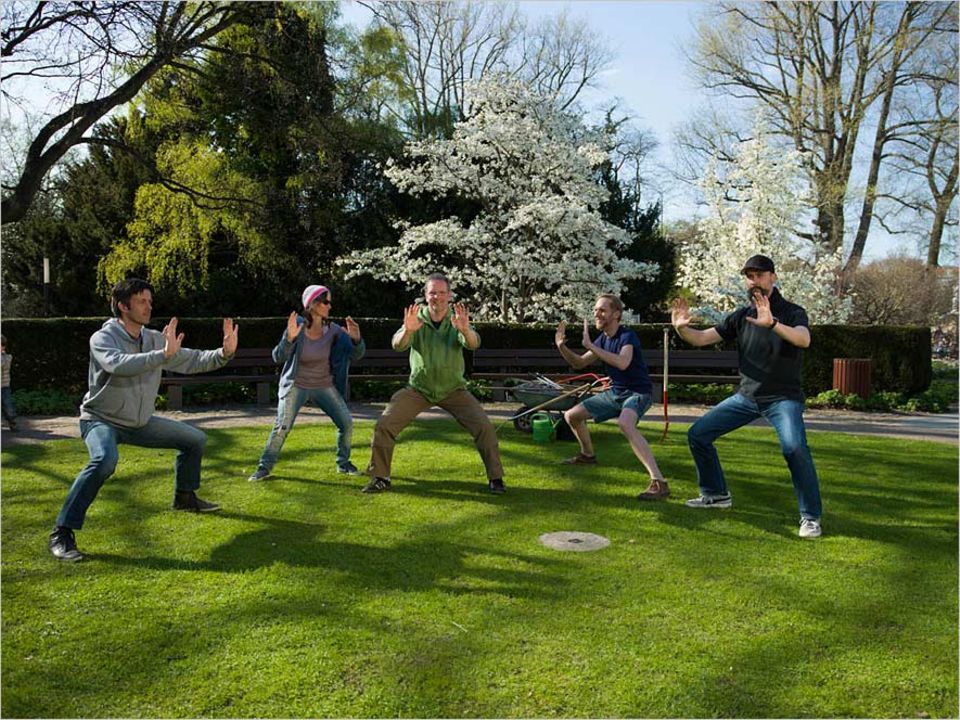 Cinq adultes font une séance de sport dans un jardin.