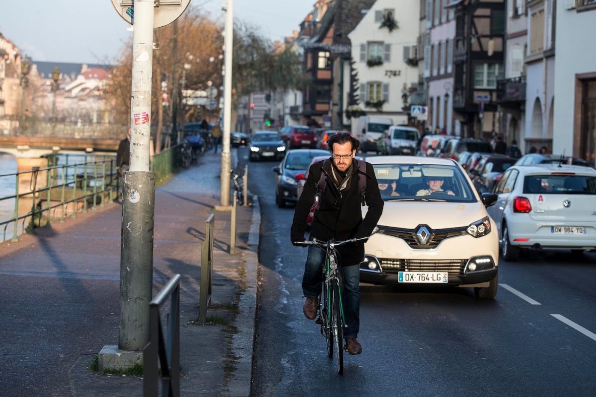 Homme faisant du vélo sur la route principale, proche d'un quai.