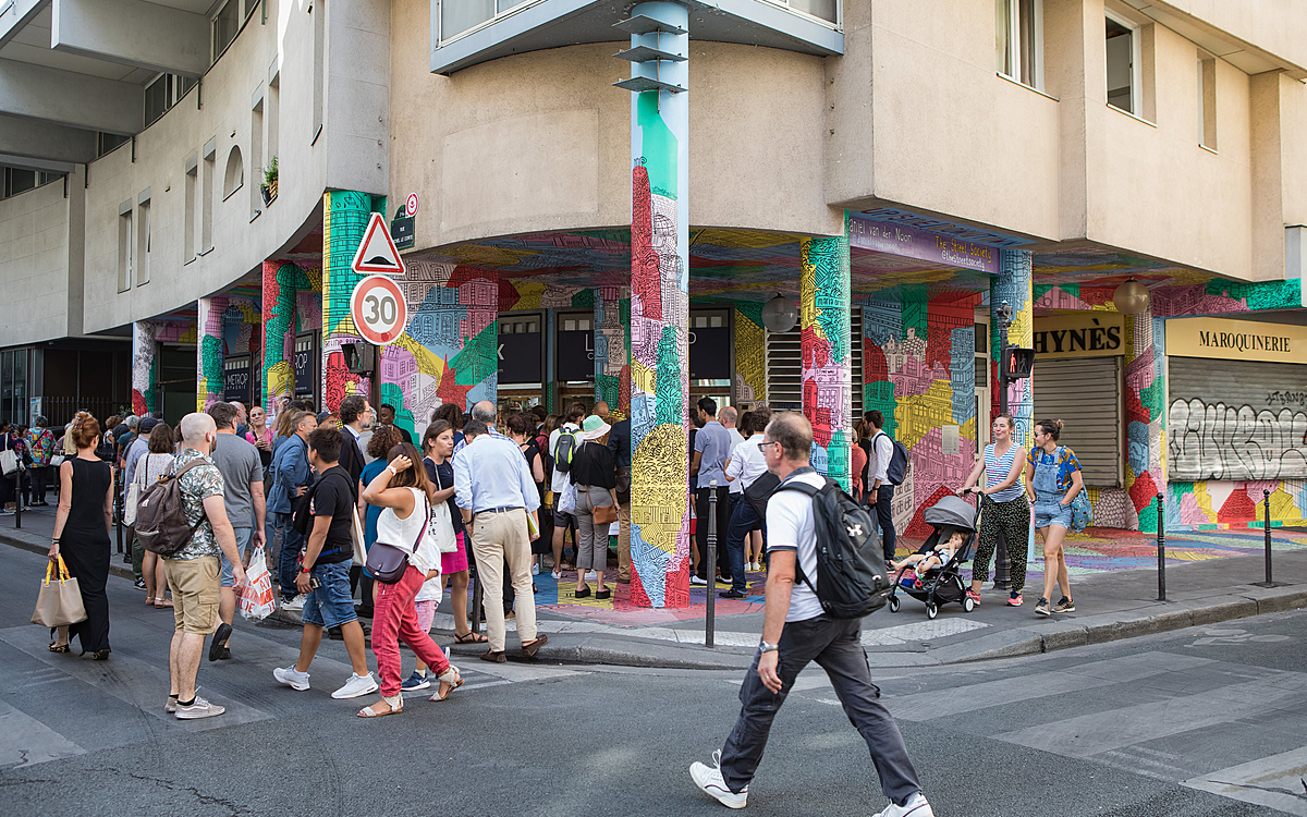 Une foule de personne observe et réagit à la fresque