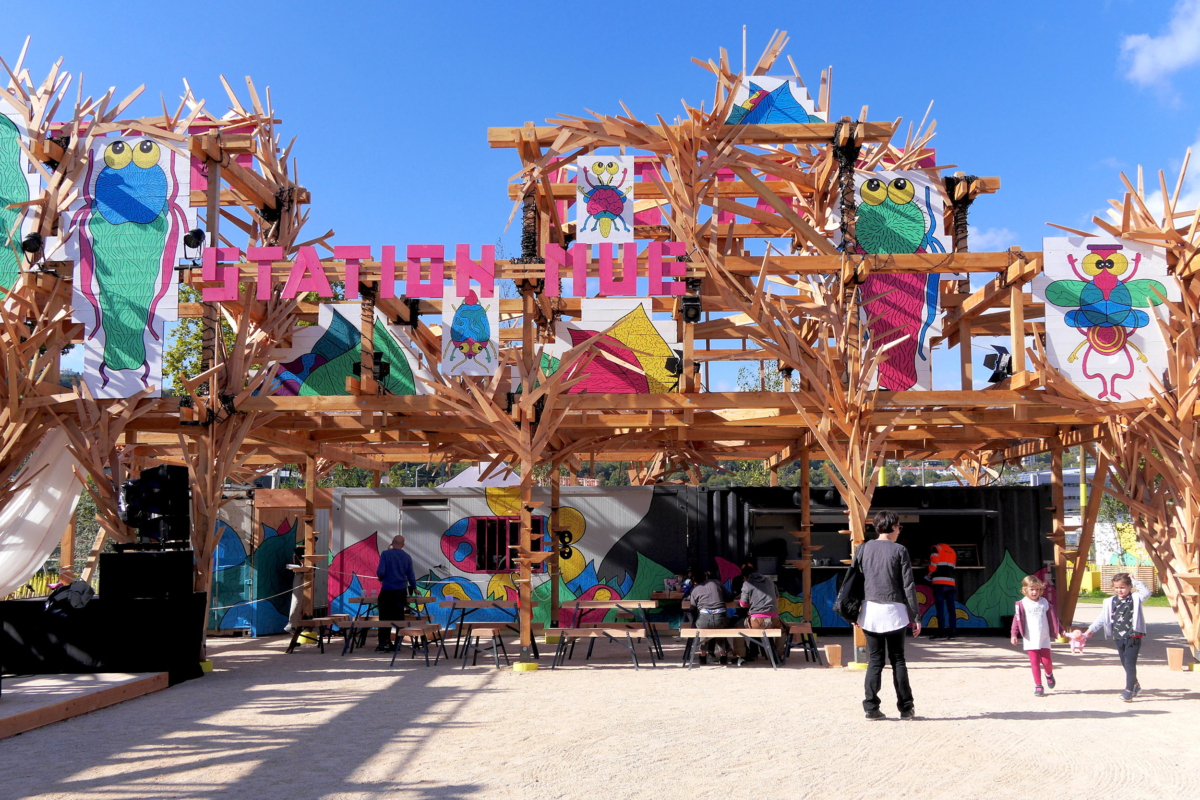 Structure en bois accueillant une buvette, une scène et des tables de pic-nic. La structure représente un dragon et est agrémentée de dessins colorés