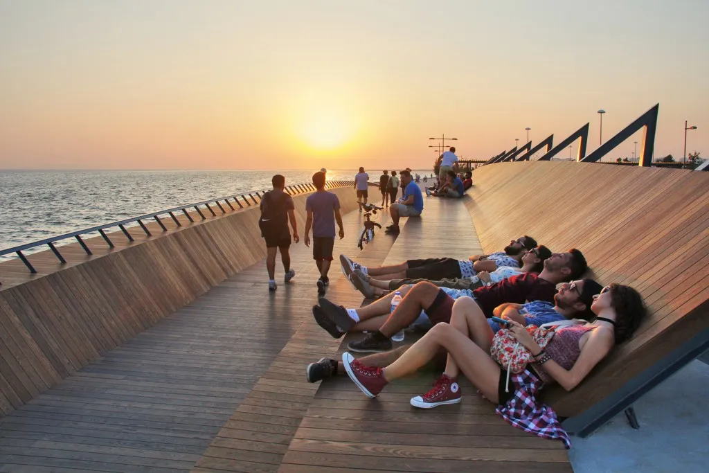 Personnes allongées sur la passerelle, avec le coucher de soleil et la mer en arrière-plan