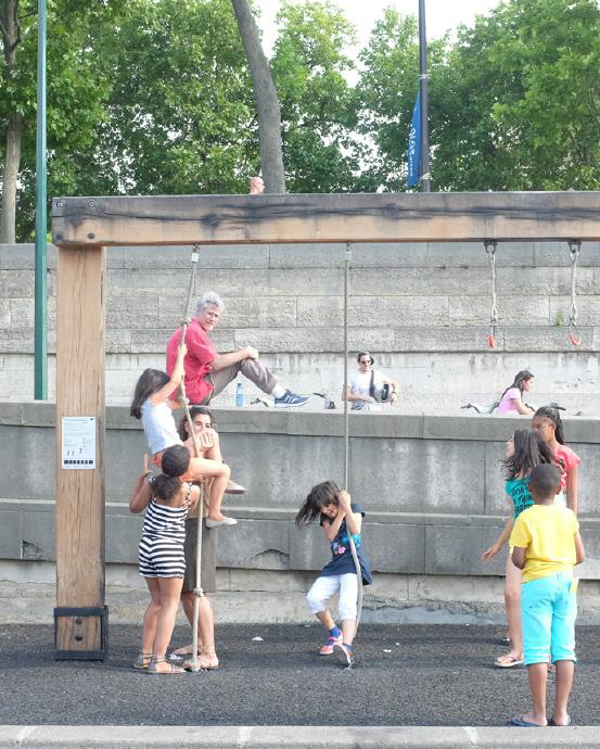 Enfants jouant à escalader à la corde sur une structure en bois installée sur les berges de la Seine