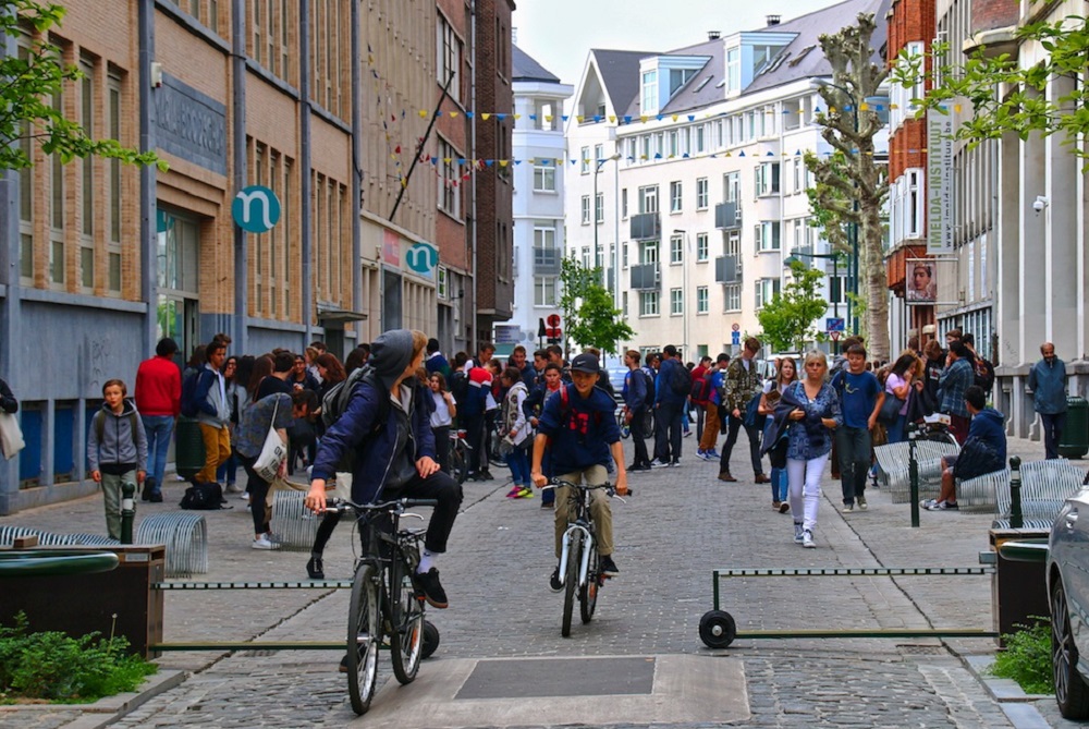 Des personnes à vélo sur une rue pavée, durant une sortie d'un collège.