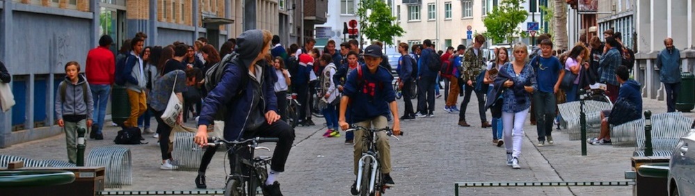 Des personnes à vélo sur une rue pavée, durant une sortie de collège.