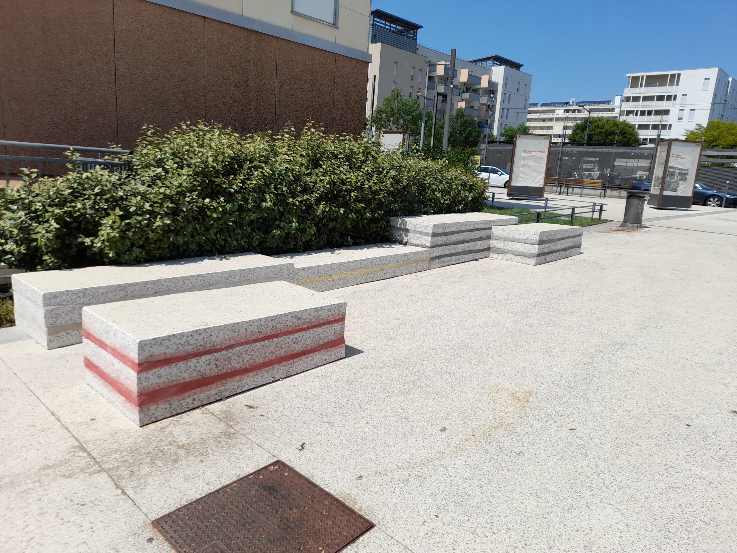 Bancs en béton créés à partir de plaques de béton réemployées. Les bancs sont de différentes hauteurs et ont des joints colorés