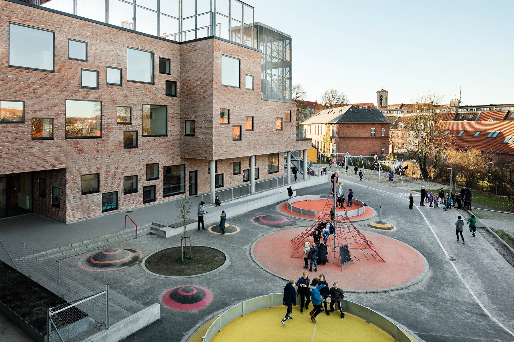 Cour d'école avec des jeux en relief, des marquages au sol, des balançoires en arrière-plan