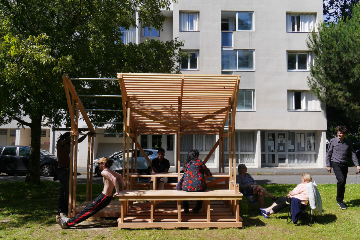 Table et ombrière en bois, plusieurs habitants avec des postures différentes